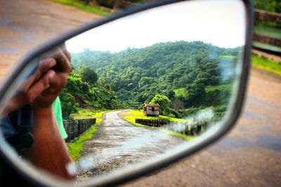 Reflection of man on side-view mirror of car