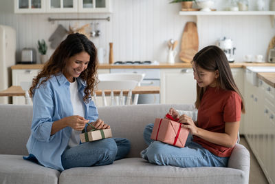 Female friends using digital tablet while sitting at home