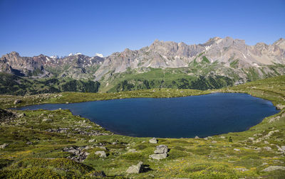 Scenic view of lake and mountains against clear blue sky