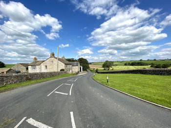 Looking down, bracewell lane, with fields, buildings, and a cloudy sky in, bracewell, skipton, uk