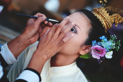 Cropped image of artist applying make-up on young woman