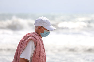 Side view of old man wearing a mask at beach