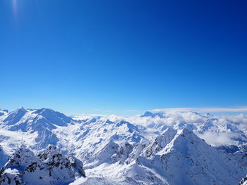 Scenic view of snow covered mountains against blue sky