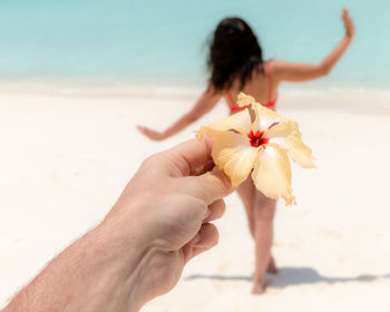 Midsection of woman holding flower on beach