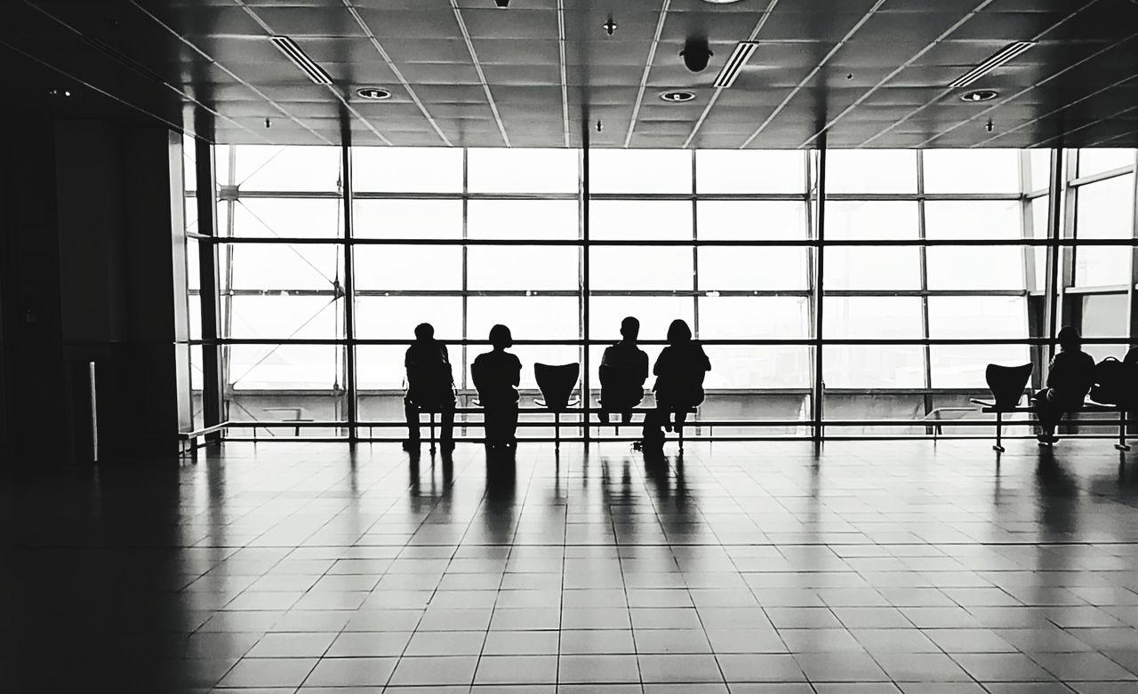 indoors, group of people, window, airport, flooring, architecture, real people, transportation, glass - material, travel, men, silhouette, transparent, walking, medium group of people, built structure, day, lifestyles, women, mode of transportation, airport departure area, tiled floor, ceiling, waiting, airport terminal