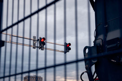 Red traffic lights and cctv camera behind metal fence