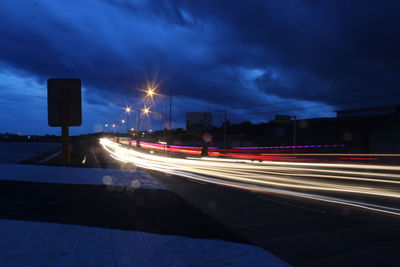 Light trails on road against sky at night