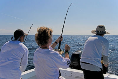 Rear view of people fishing in boat on sea