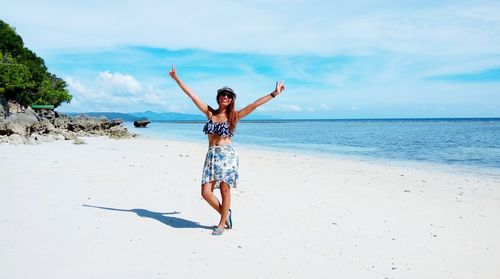 Full length of woman with arms outstretched standing at beach