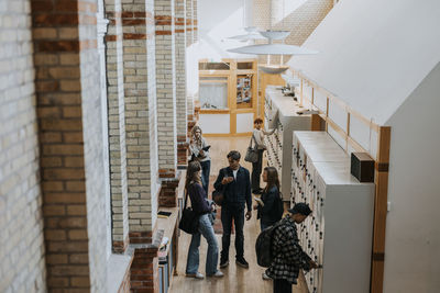 High angle view of male and female students by locker in corridor