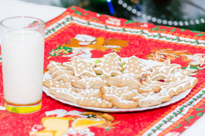 Close-up of milk glass by gingerbread cookies in plate on table