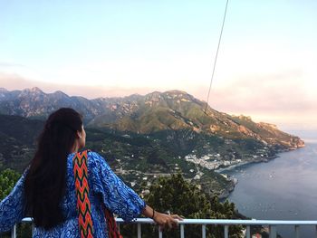 Woman looking at view while standing at observation point against sky