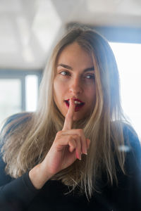 Portrait of woman with finger on lips at home