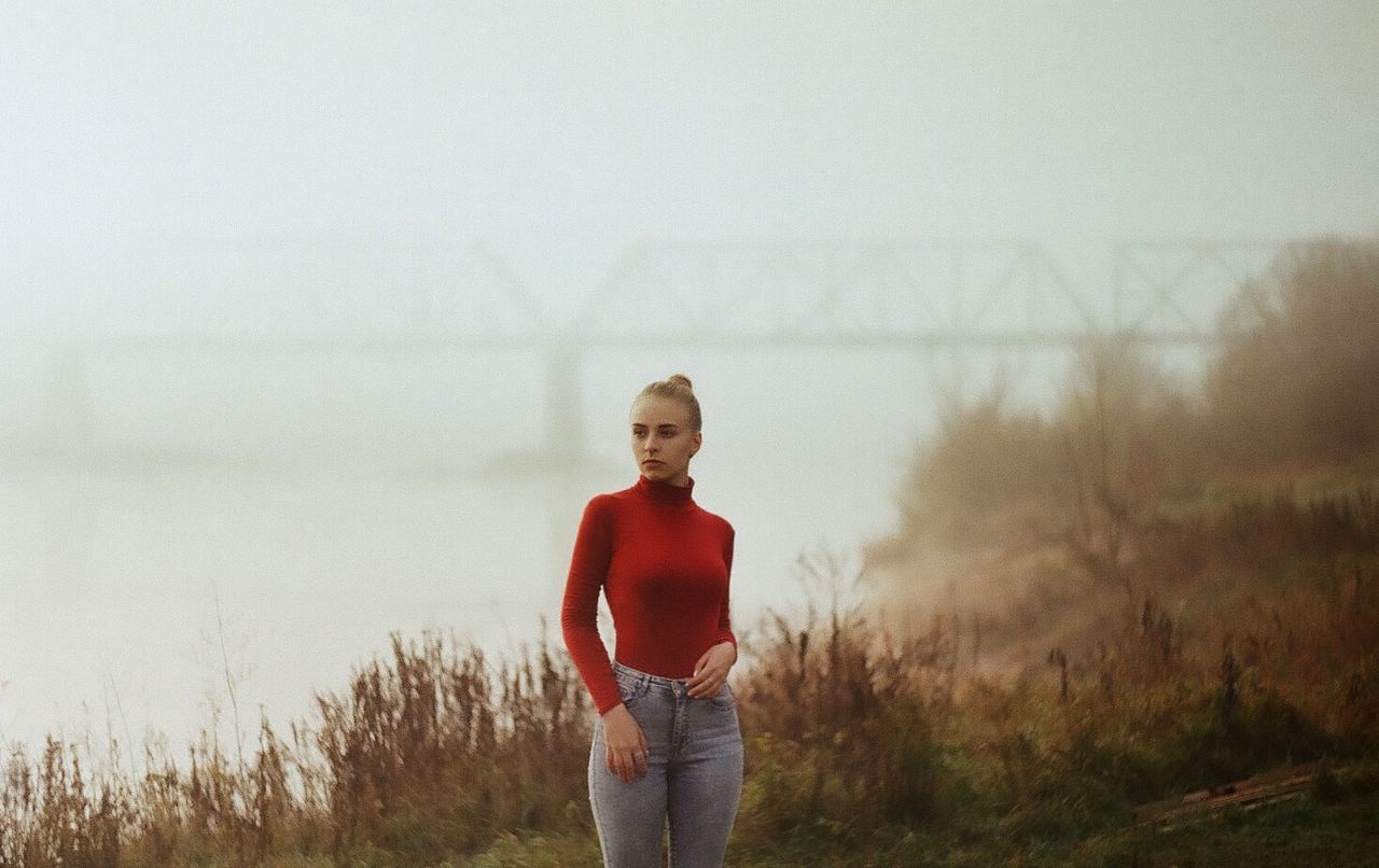 FULL LENGTH PORTRAIT OF YOUNG WOMAN STANDING ON FIELD