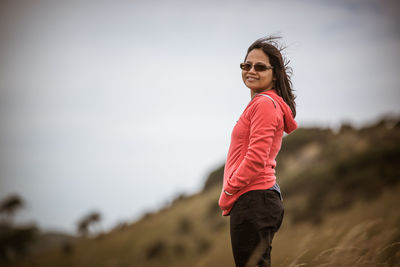 Young smiling woman standing on grassy hill