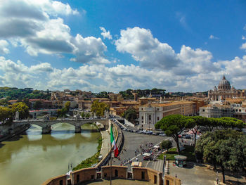 High angle view of bridge over river by buildings in city against sky