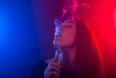 Portrait of young woman smoking at night