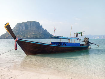 Boat moored on beach against sky