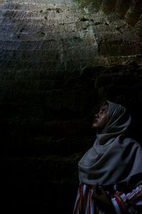 Woman in hijab looking up by wall