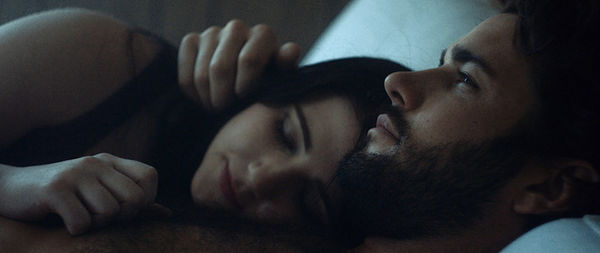 Close-up of thoughtful man lying with girlfriend on bed