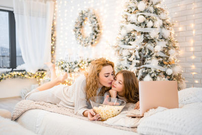 Portrait of smiling woman sitting on bed at home