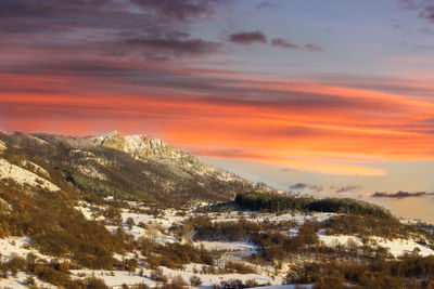 Scenic view of snow covered mountain against orange sky