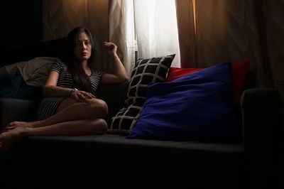 Young woman sitting on sofa at home