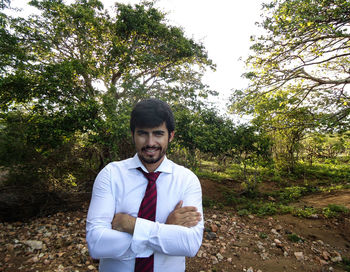 Portrait of young man standing against trees