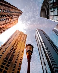 Low angle view of lamp post by buildings against sky