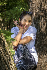 Portrait of smiling young man on tree trunk