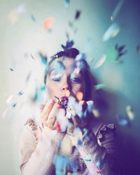 Portrait of mid adult woman blowing confetti