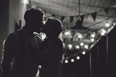 Silhouette couple kissing against illuminated lights