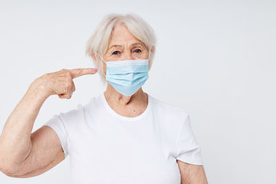 Portrait of young man wearing mask against white background