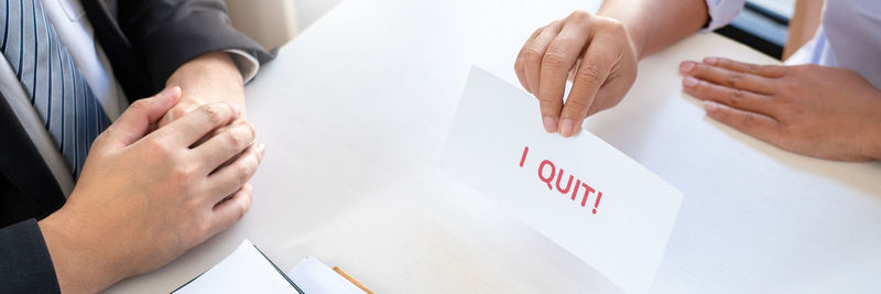 Midsection of man holding paper with text on table