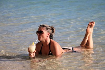 Woman having drink while relaxing at beach