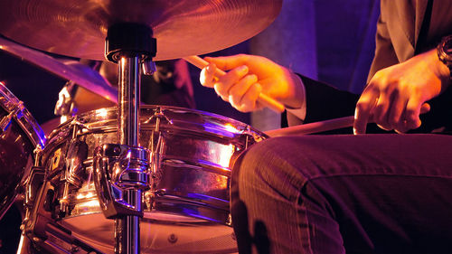Midsection of man playing drum during music concert