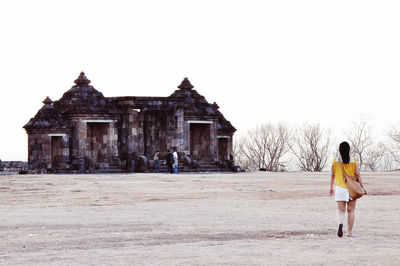 Full length rear view of woman walking against building