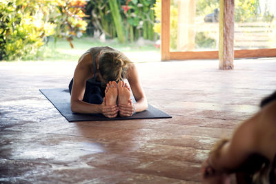 Woman practicing seated forward bend pose in yoga studio