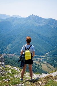 A woman looks at the valley from the top of a mountain