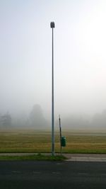 Road passing through field in foggy weather