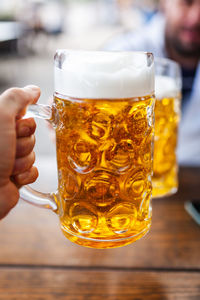 Close-up of hand holding glass of beer on table