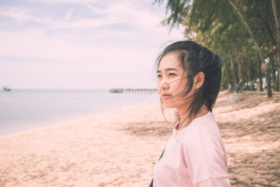 Portrait of beautiful woman at beach against sky