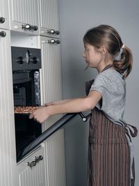 Food theme. cooking pizza. a teenager puts a pizza in the kitchen oven 