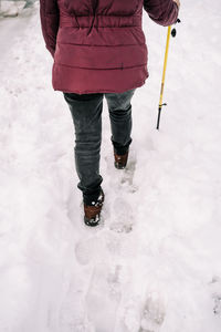 Low section of person standing on snow covered land