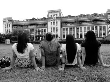 Rear view of friends sitting in city against clear sky