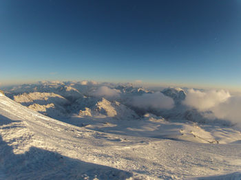 Aerial view of snow covered landscape against blue sky