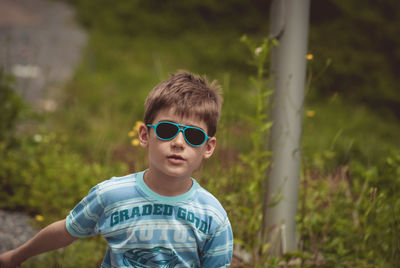 Portrait of boy wearing sunglasses walking by field