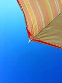 Cropped parasol against clear blue sky