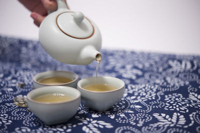 Close-up of hand pouring tea cup on table