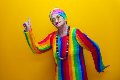 Portrait of senior woman dancing against yellow background